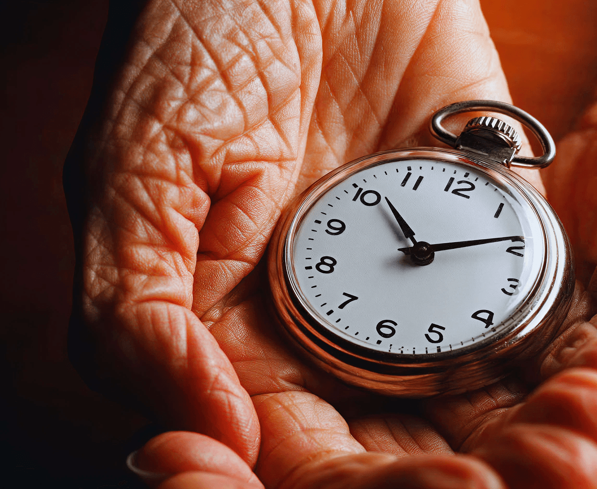 A stopwatch pointing to 10 minutes past 10, held up by a pair of wrinkled hands